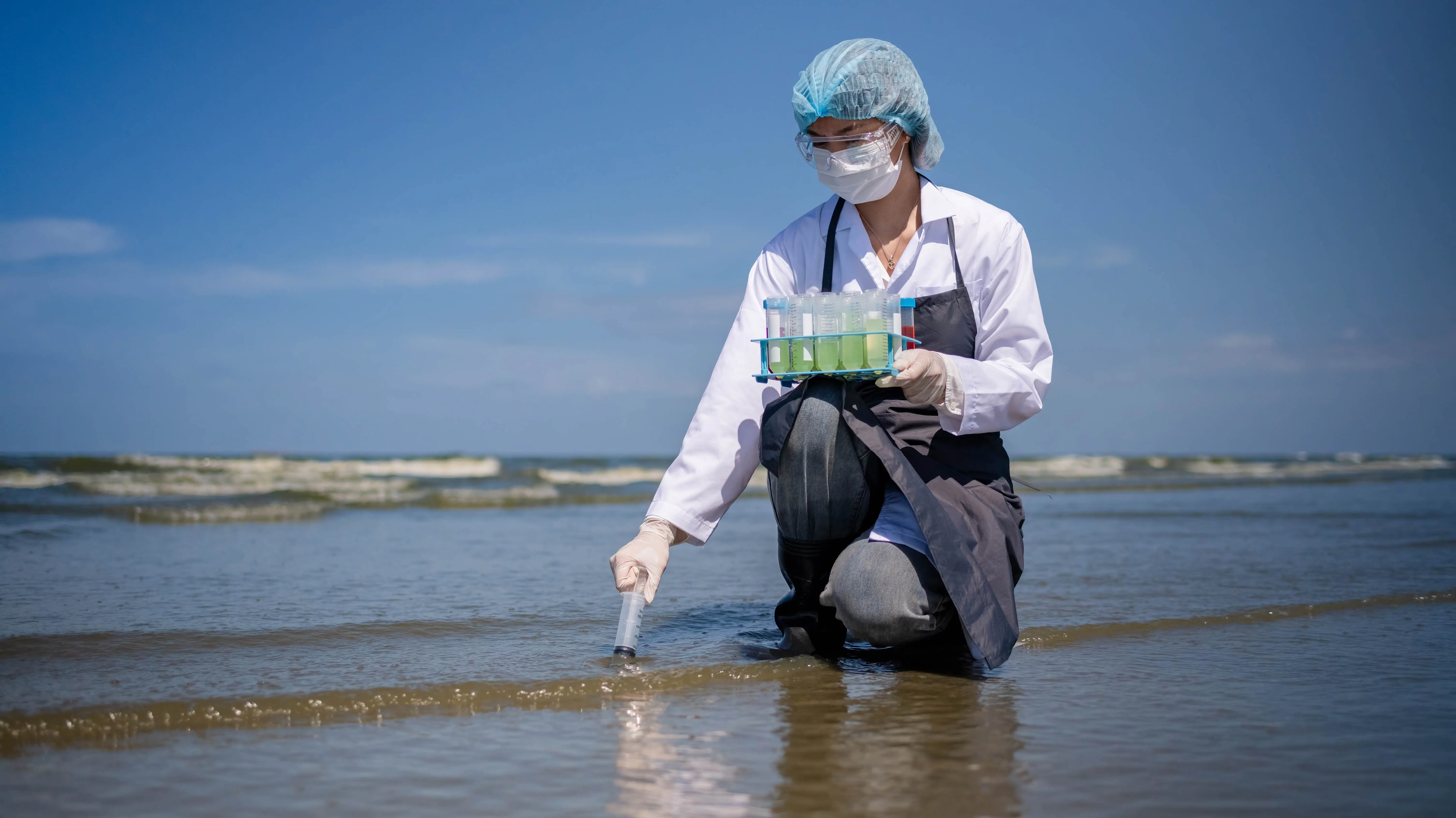 Wissenschaftliche Fachkraft, die bei der Arbeit die Wasserqualität analysiert und dabei eine Brille und einen Schutzhandschuh trägt.